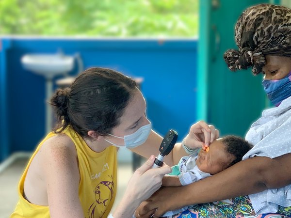 Woman using tool to look in infant's eyes